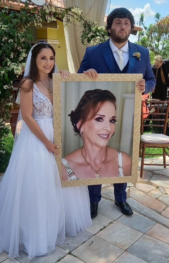 2022 - Amanda e Lucas segurando quadro em homenagem à sua sogra, Maria José (Zezé)