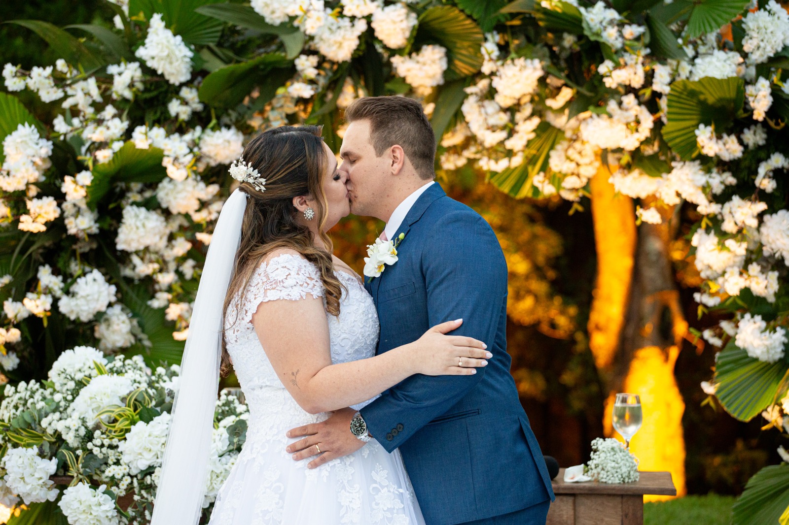 Ao fundo, arranjo com folhas de laranjeira, hortênsias brancas, e Áster Mariana