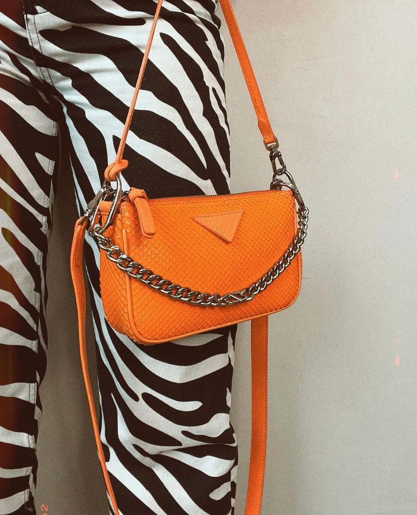 Macacão de zebra com uma bolsa laranja ou caramelo.