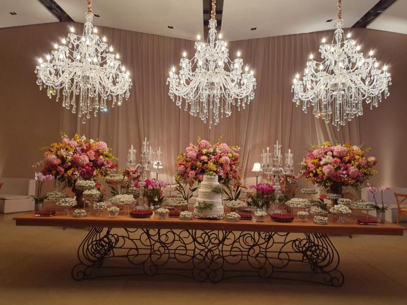 Três enormes lustres de cristais davam luz a mesa dos doces