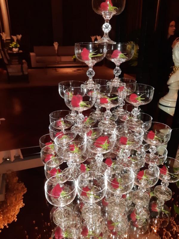 O serviço  de champanhe, em formato de cascata, compunha contido  um botão  de rosa vermelha,  era parte do cenário glamuroso.
